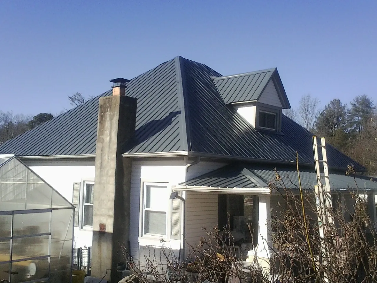 Dark blue standing seam metal roof on a white farmhouse with dormer — Slate & Tile Roof Repair by Roofing Brothers in Stewartstown