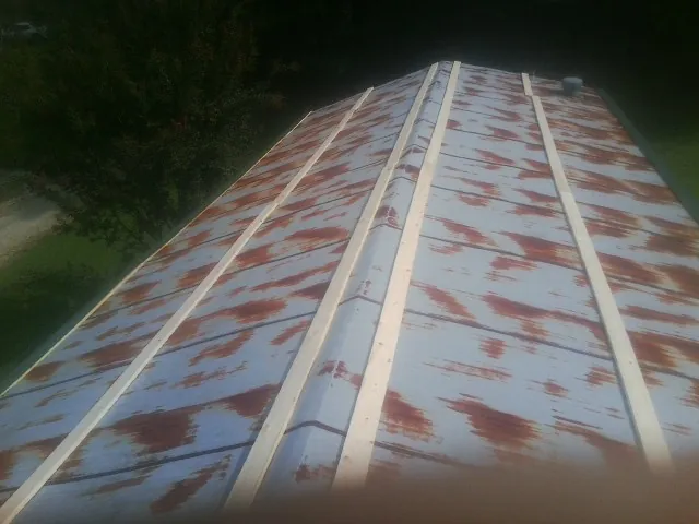 Rusted metal roof panels with new wood purlins before replacement — Storm Damage Roof Repair in Stewartstown by Roofing Brothers