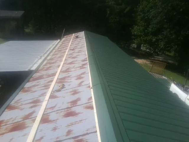Old rusted panels beside newly installed green metal roofing — Wind Damage Roof Repair by Roofing Brothers in Stewartstown