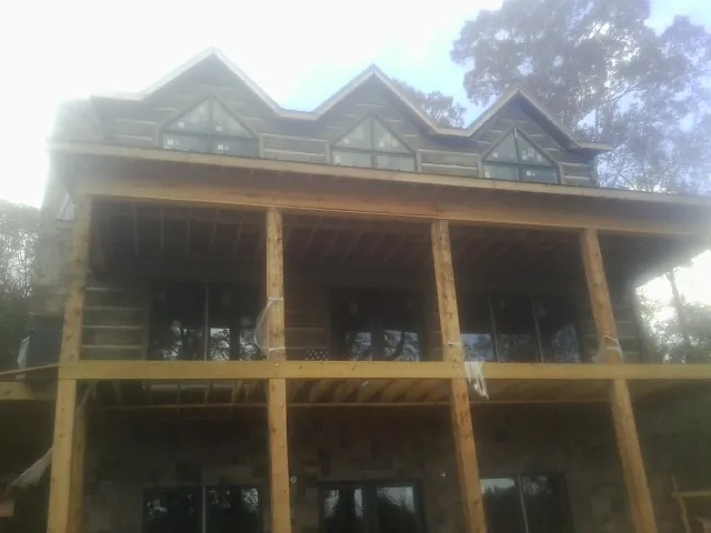 Dormers and porch framing on a large log home under construction — Roof Coating work by our crew in Stewartstown