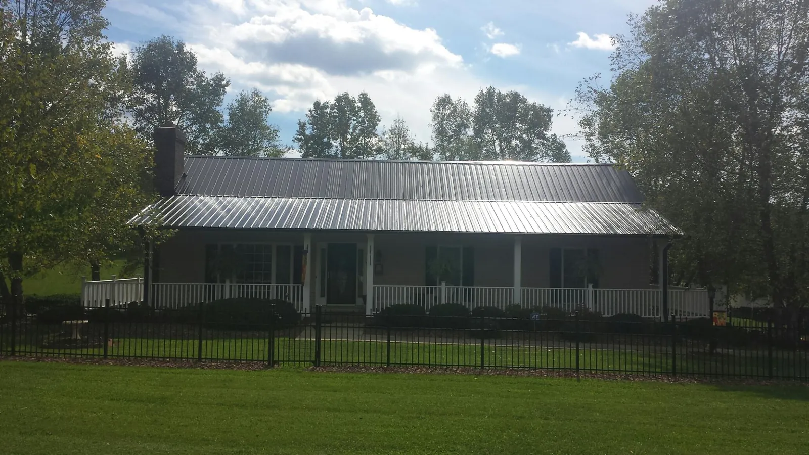 Gray metal roof on a brick ranch with a full width front porch — Gutter Guard Installation work by our crew in Stewartstown