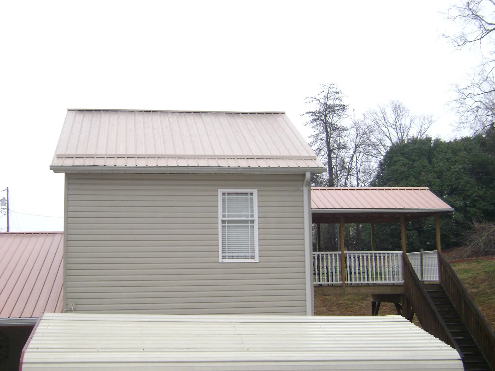 Tan metal roofs on a two story addition and attached porch, from a Roof Replacement job in Stewartstown