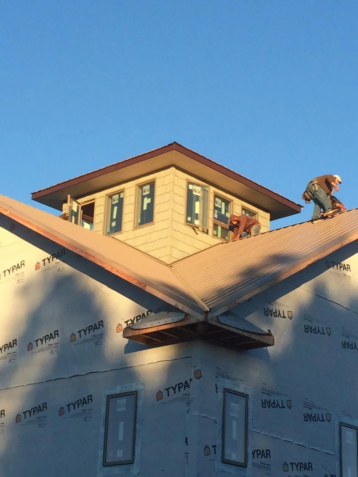 Roofers working around a rooftop cupola on a new metal roof at sunset — Roof Waterproofing in Stewartstown by Roofing Brothers